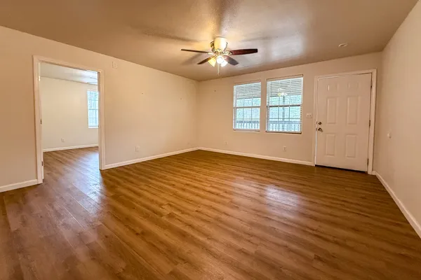 a view of an empty room with wooden floor and a window