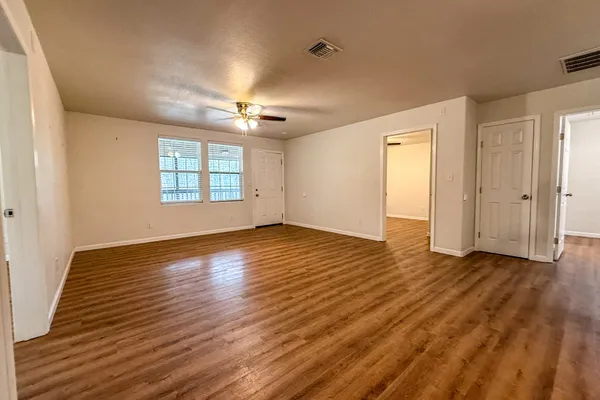 an empty room with wooden floor and windows