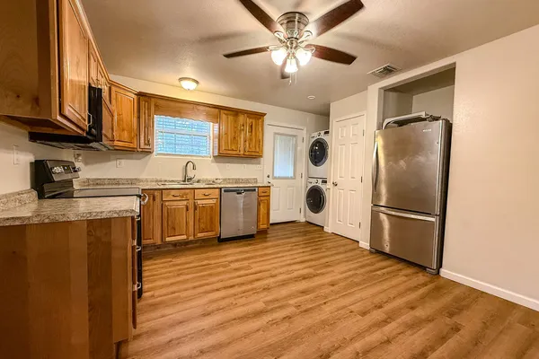 a kitchen with stainless steel appliances granite countertop a refrigerator a stove a sink and white cabinets with wooden floor