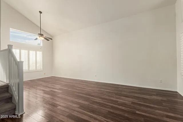 a room with wooden floor a ceiling fan and window