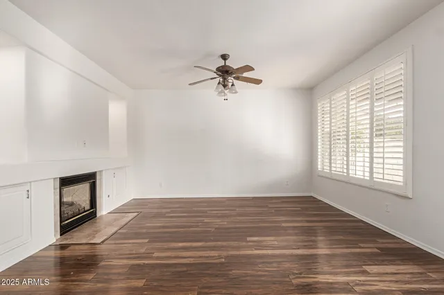 a view of an empty room with a window and hardwood floor