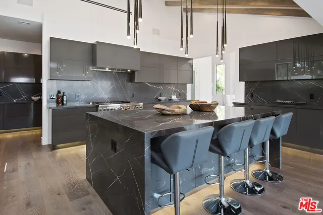 a living room with stainless steel appliances kitchen island granite countertop a table chairs in it and wooden floors