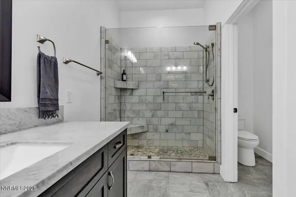 a bathroom with a granite countertop sink a toilet and shower