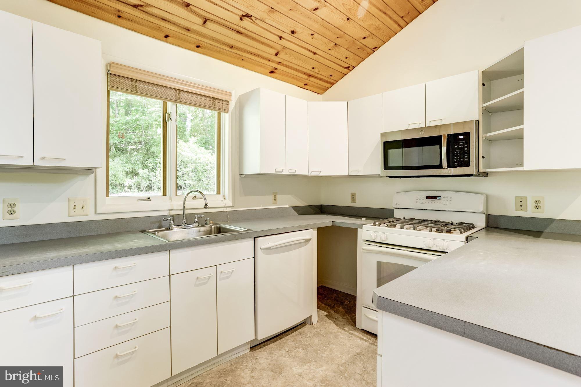4511 Clifton Road Baltimore, MD 21216 - Photo 4 of 35 a kitchen with cabinets appliances a sink and a window