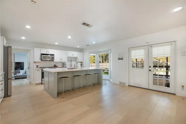 a large white kitchen with stainless steel appliances granite countertop lots of white cabinets