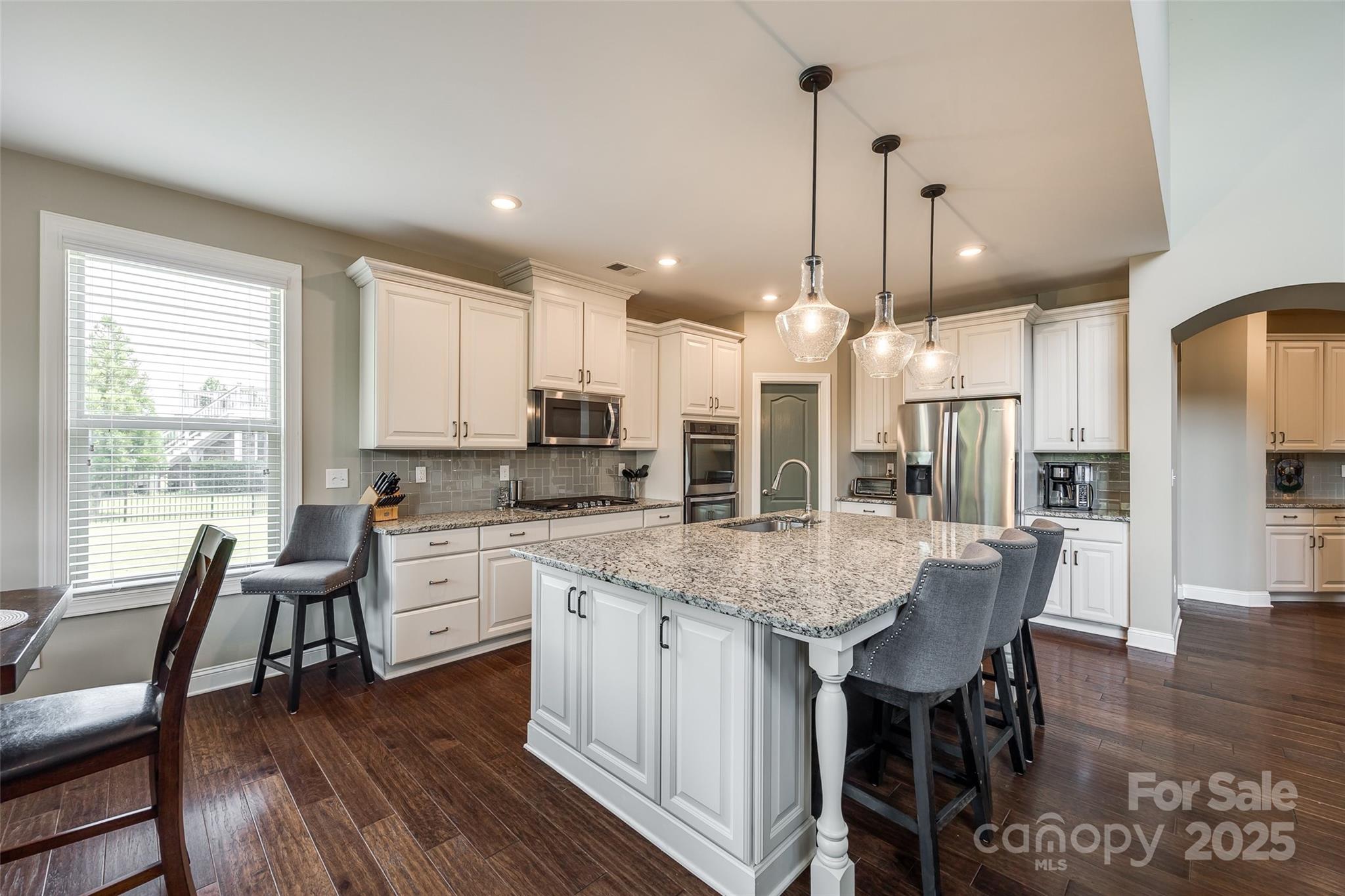 4220 Thames Circle Fort Mill, SC 29715 - Photo 13 of 44 a kitchen with stainless steel appliances granite countertop wooden floor dining table and chairs