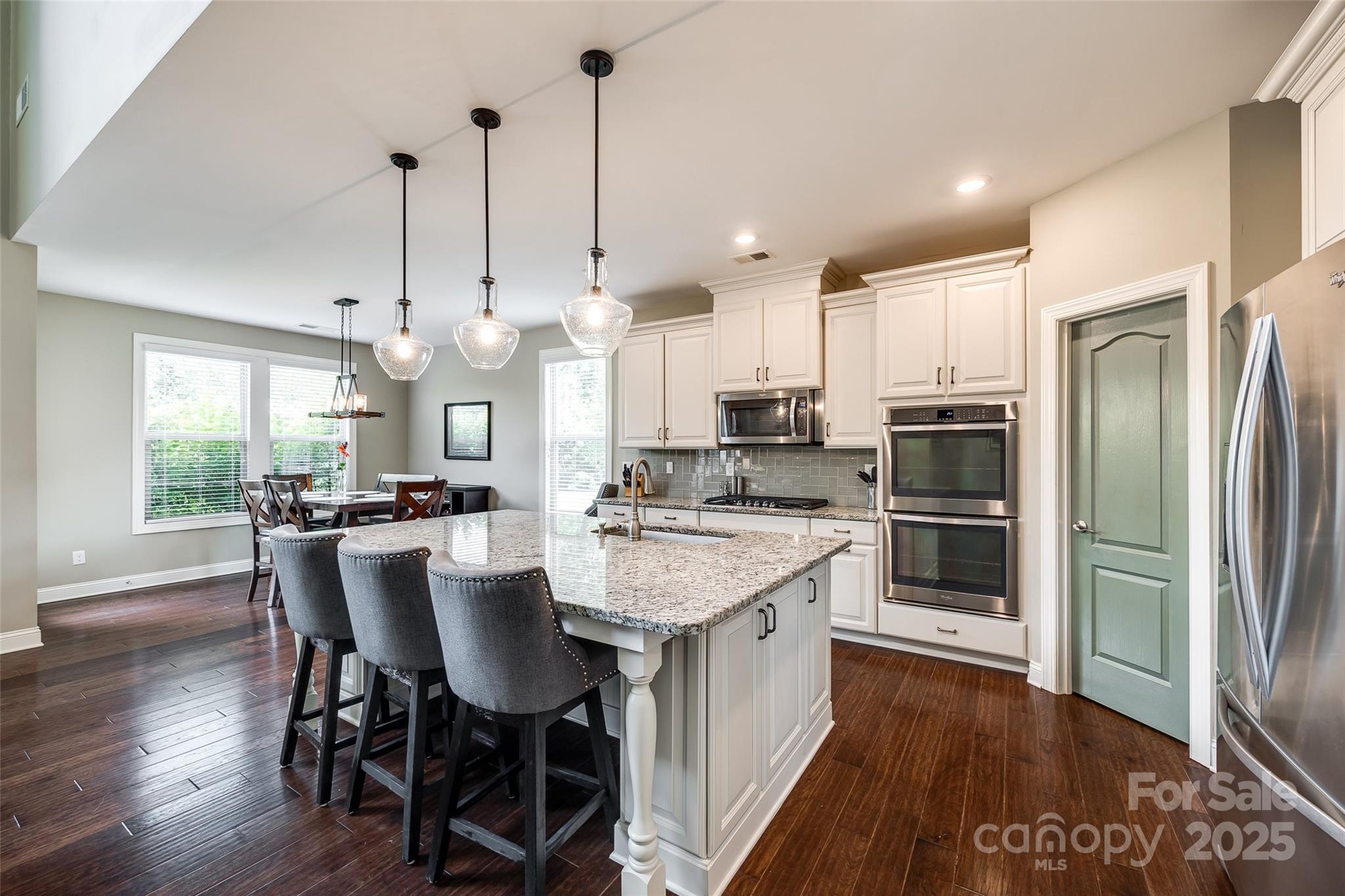 4220 Thames Circle Fort Mill, SC 29715 - Photo 14 of 44 a kitchen with stainless steel appliances kitchen island granite countertop a refrigerator a stove a sink a dining table and chairs with wooden floor