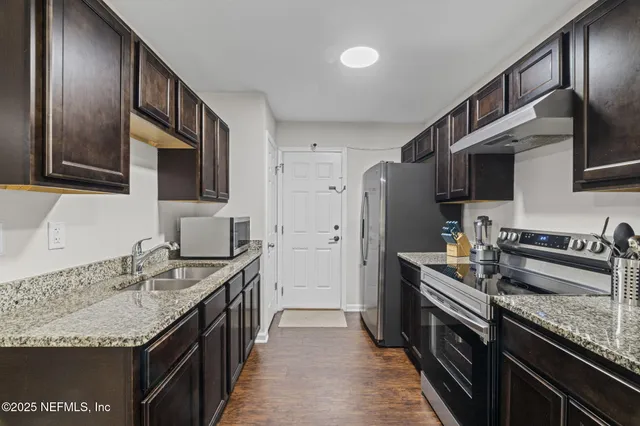 a kitchen with granite countertop stainless steel appliances a sink stove and refrigerator