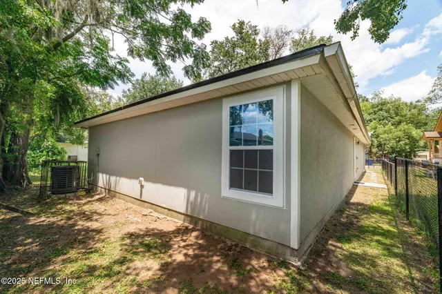 a view of a house with a yard plants and large tree