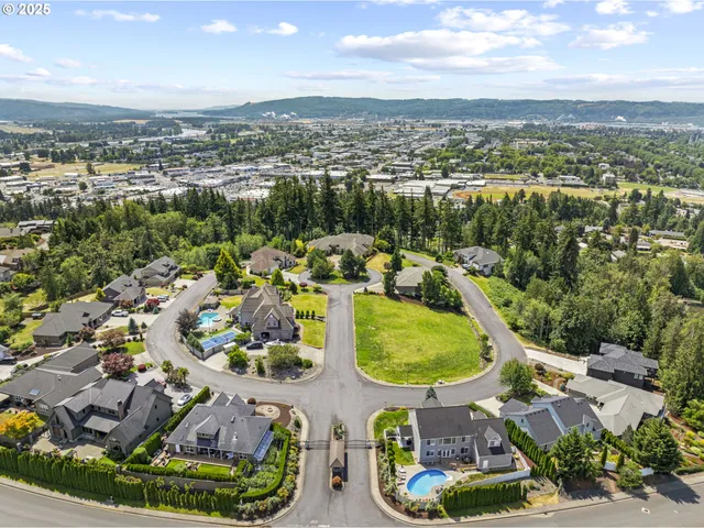 an aerial view of a residential houses with outdoor space and a lake view in back