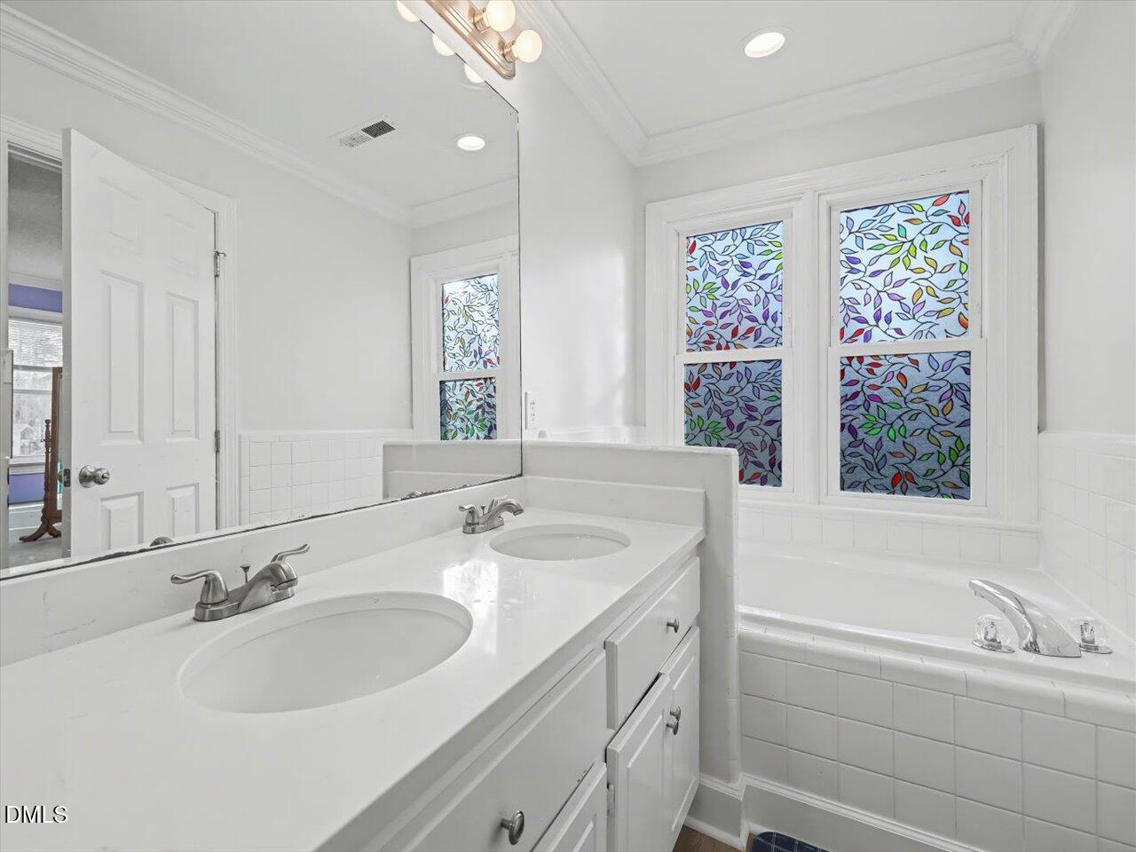4828 Forest Highland Drive Raleigh, NC 27604 - Photo 12 of 27 a bathroom with a double vanity sink window and a bathtub