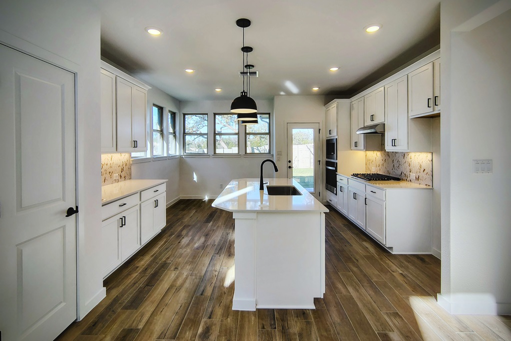 1804 Spg Mountain Cove Georgetown, TX 78628 - Photo 4 of 32 a large white kitchen with kitchen island a stove a sink a refrigerator and cabinets