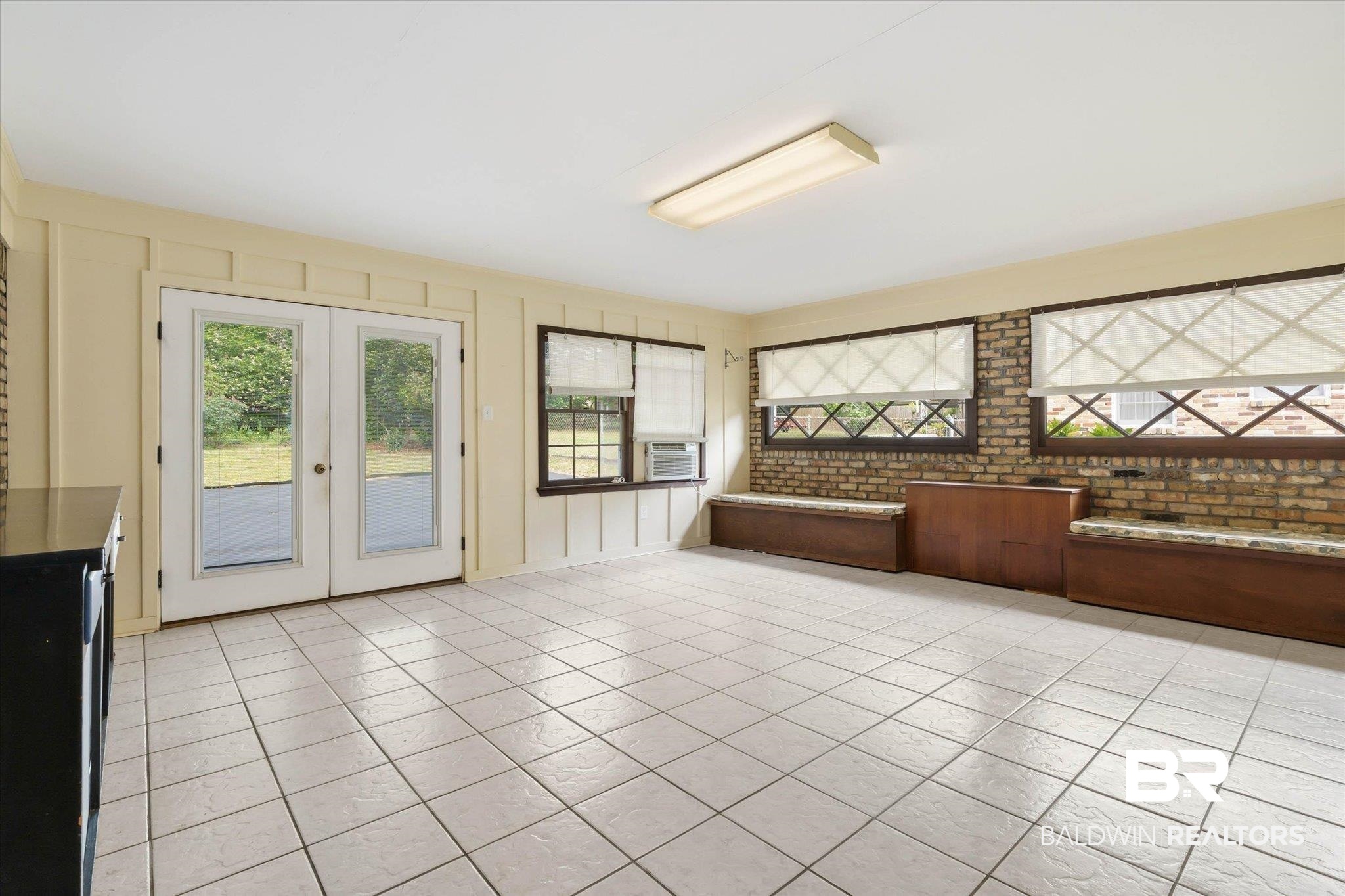 1182 Ginger Drive Mobile, AL 36693 - Photo 28 of 37 Spacious room featuring light-toned tile flooring, white French doors, and exposed brick accents