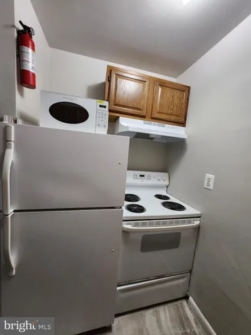 a utility room with stainless steel appliances wooden cabinets and a sink