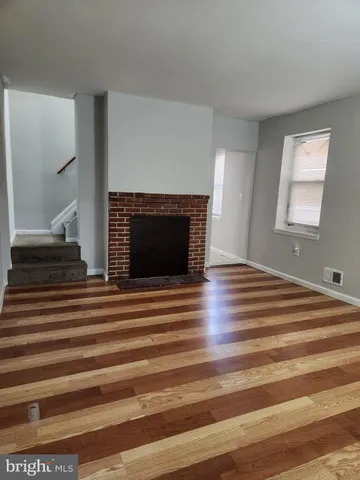 a view of an empty room with window and wooden floor