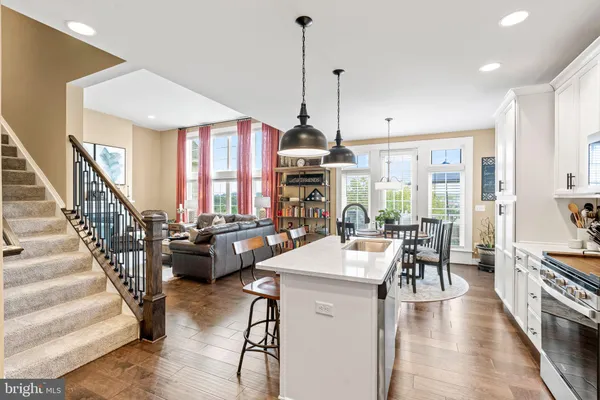 a kitchen with stainless steel appliances granite countertop a refrigerator a stove top oven a sink dishwasher a dining table and chairs with wooden floor