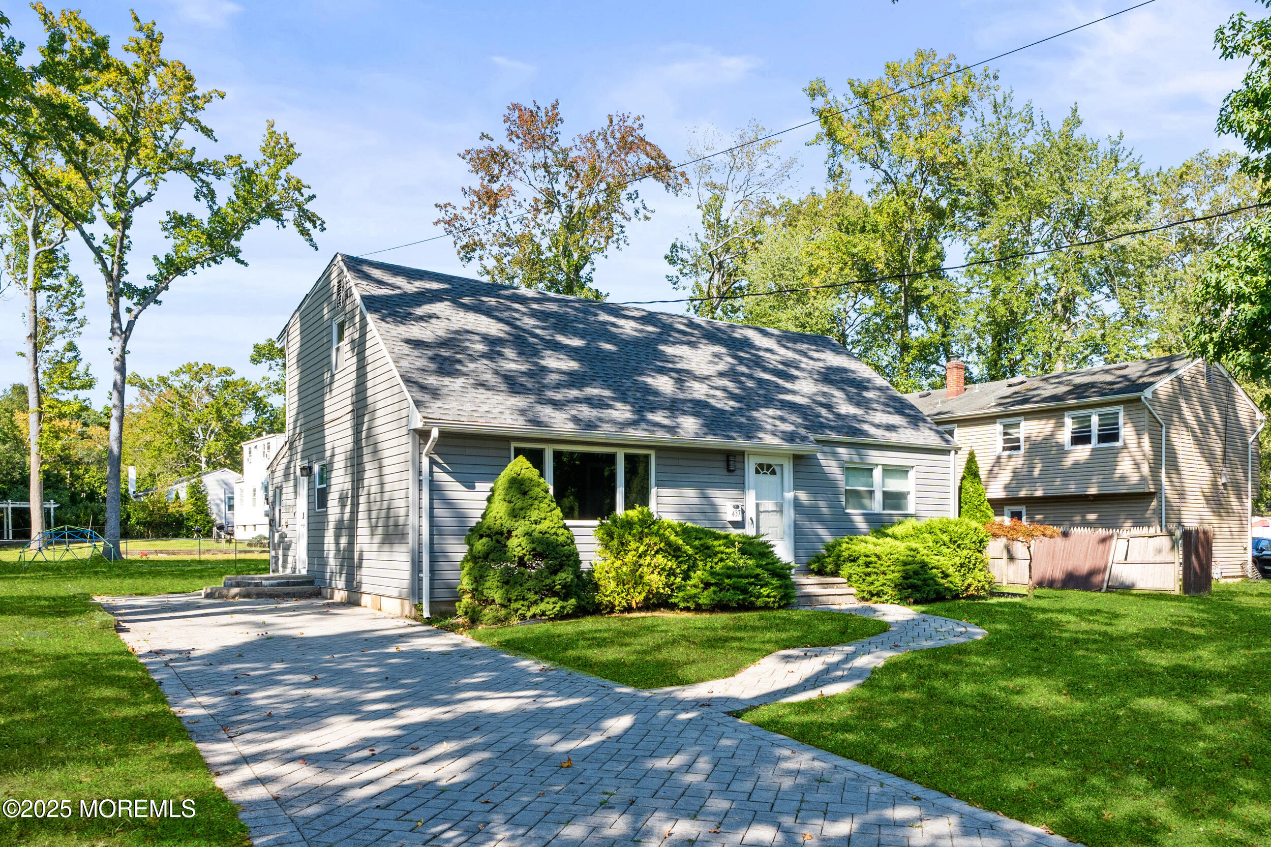 a view of a brick house with a yard plants and a large tree