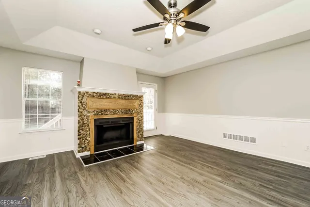an empty room with windows fireplace and wooden floor