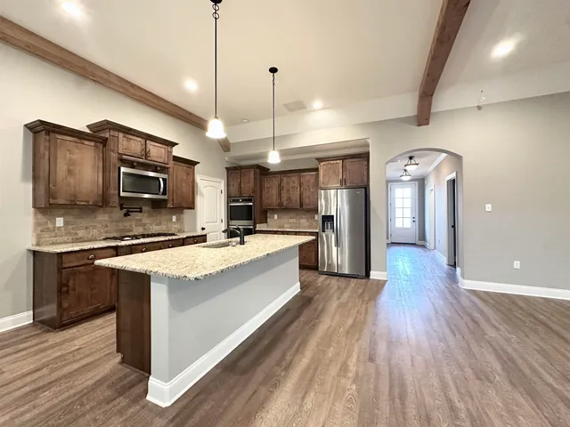a large kitchen with stainless steel appliances kitchen island wooden cabinets and granite counter tops
