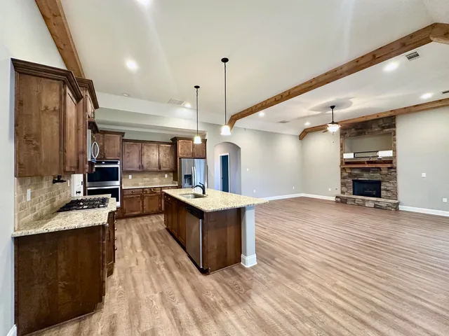 a large kitchen with stainless steel appliances and wooden floor