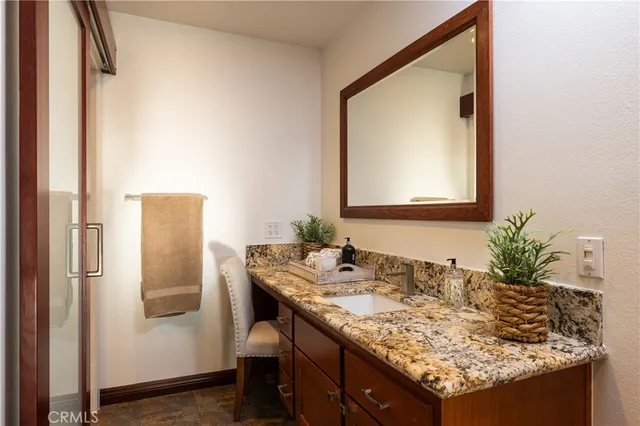 a bathroom with a granite countertop sink and a mirror
