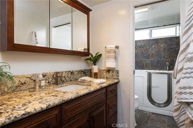 a bathroom with a granite countertop sink and a mirror