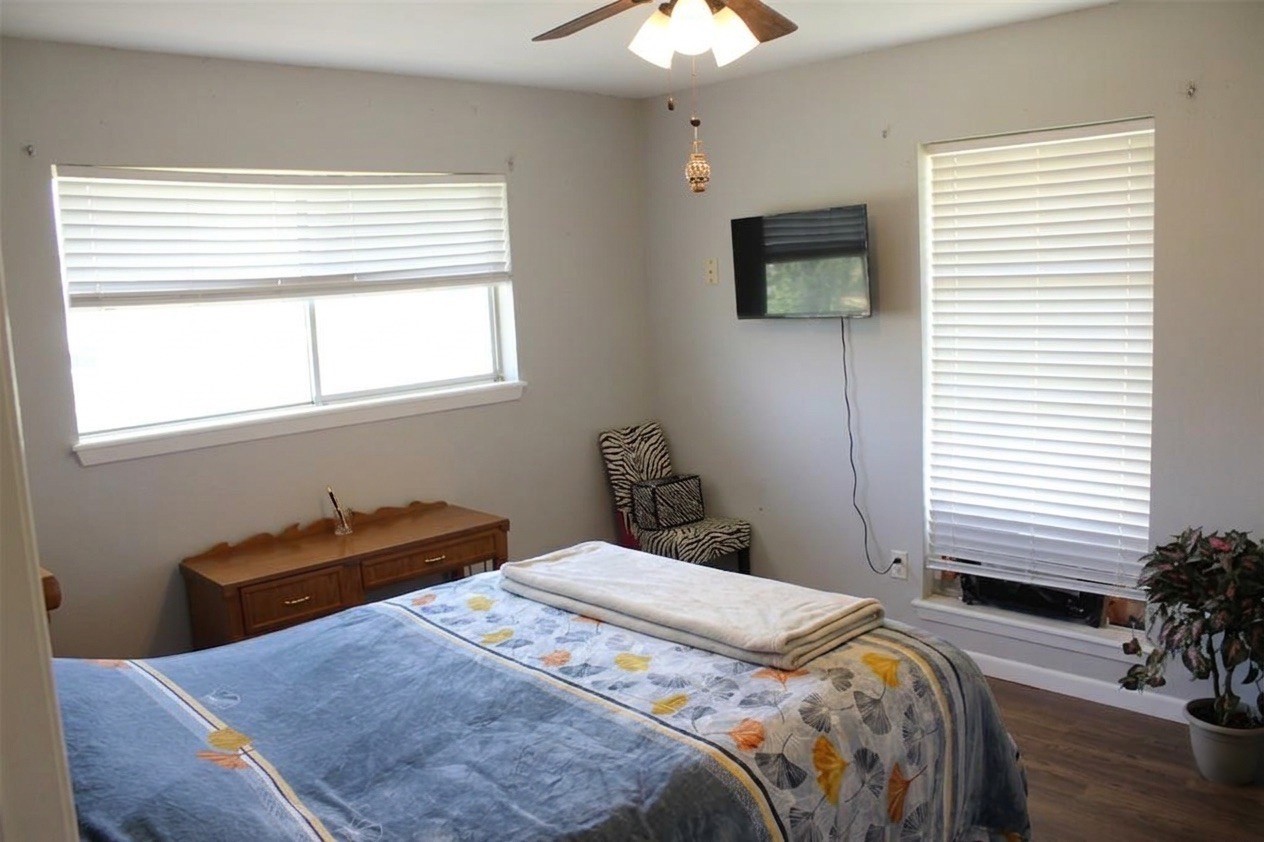 206 Riverside Street Highlands, TX 77562 - Photo 7 of 12 Generously sized secondary bedroom filled with natural light from dual windows, ceiling fan, and dark laminate flooring, comfortable and ready for any buyer's vision.