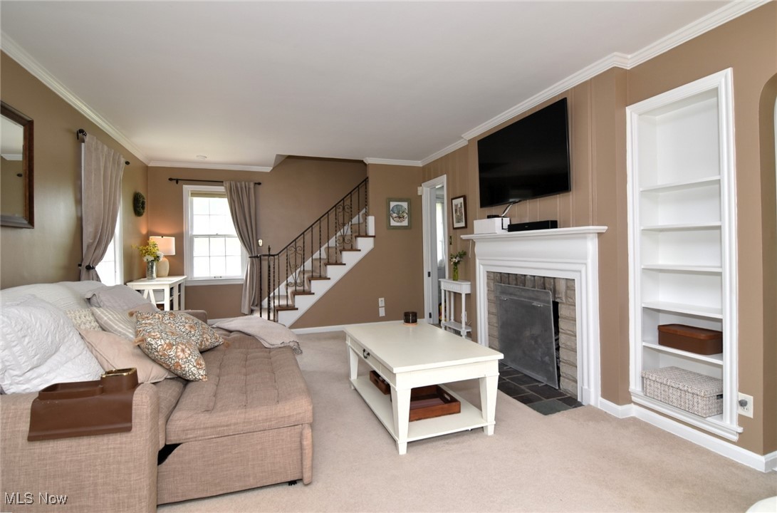2278 Traymore Road Cleveland, OH 44118 - Photo 10 of 49 Living room featuring crown molding, a fireplace with flush hearth, carpet floors, stairs, and built in features