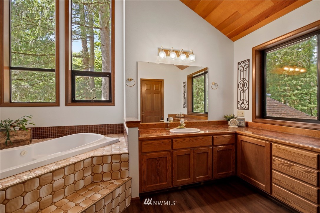 20830 Southeast 145th Street Renton, WA 98059 - Photo 16 of 39 a spacious bathroom with a sink a large mirror and a bathtub next to a window