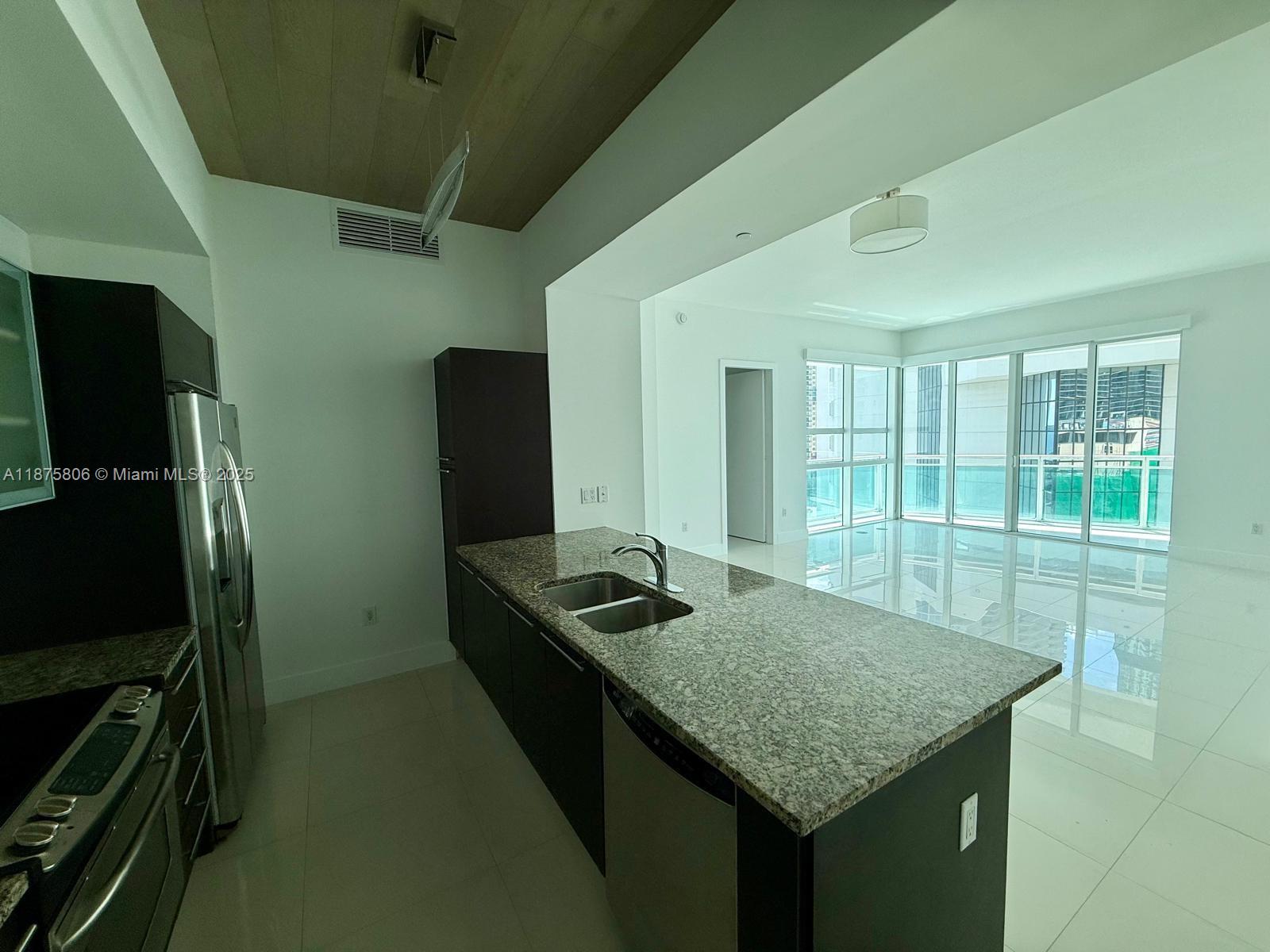 951 Brickell Avenue, Unit 1010 Miami, FL 33131 - Photo 2 of 23 a kitchen with granite countertop kitchen island stainless steel appliances a sink stove and refrigerator