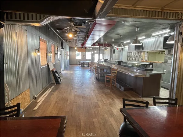 a dining hall with stainless steel appliances kitchen island granite countertop a table chairs and a window