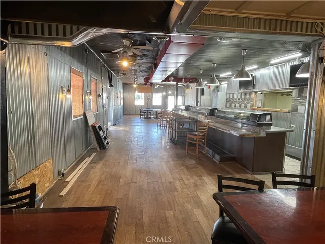 a dining hall with stainless steel appliances kitchen island granite countertop a table chairs and a window