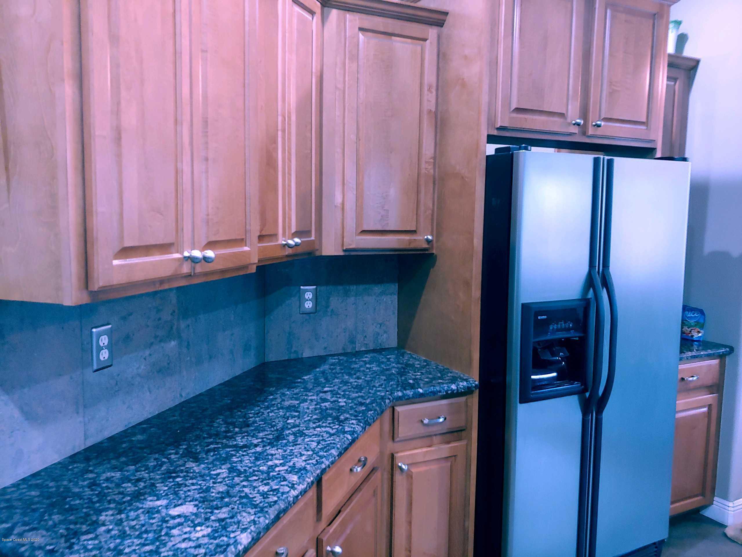 6791 Hartford Road Cocoa, FL 32927 - Photo 20 of 43 a kitchen with granite countertop wooden cabinets and stainless steel appliances