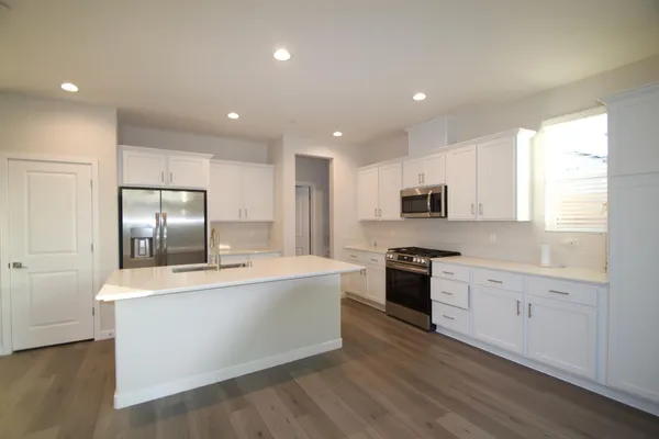 a large kitchen with stainless steel appliances granite countertop a large counter top and a stove with wooden floor