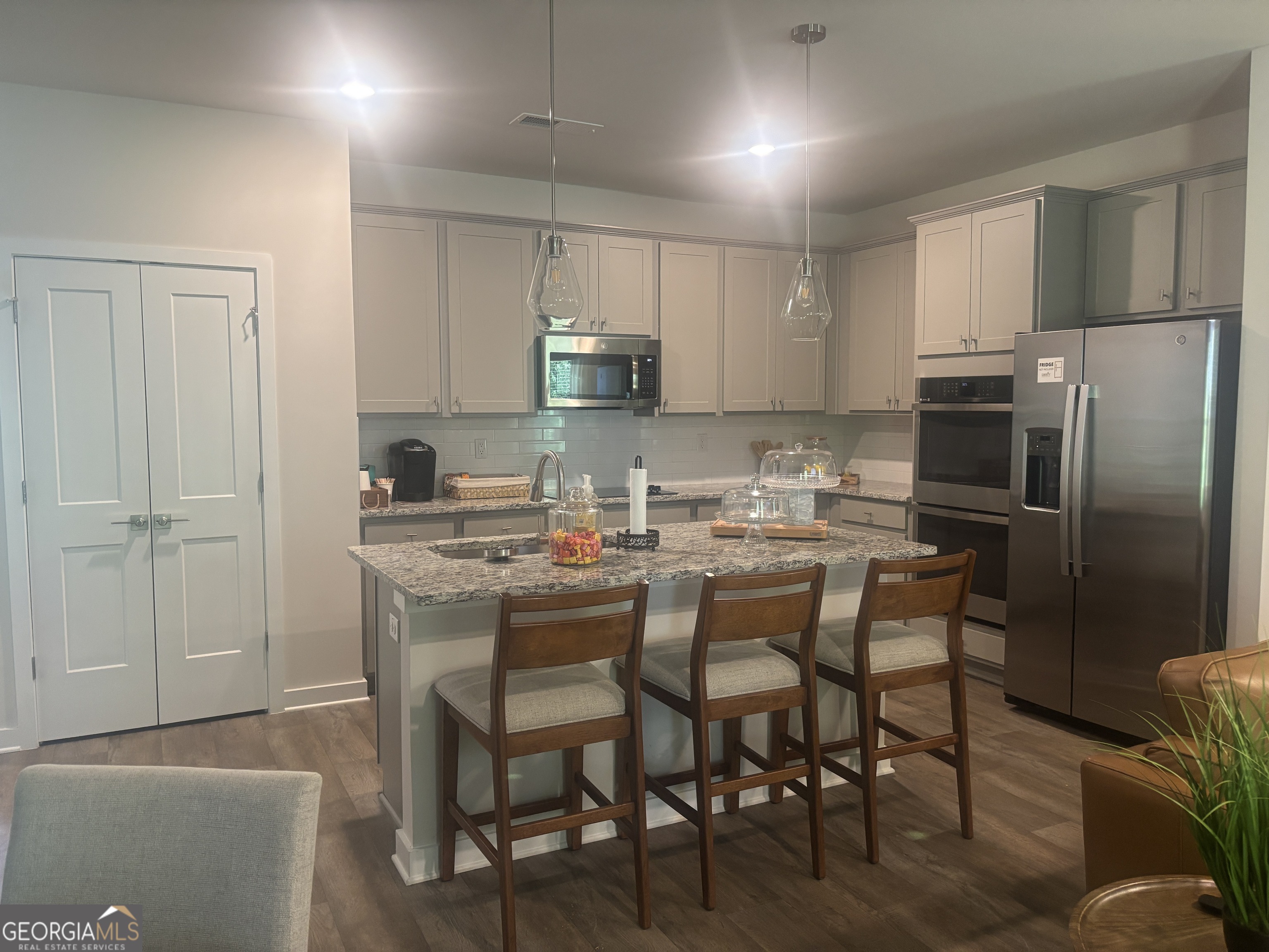 5355 Tolar Road South Fulton, GA 30213 - Photo 3 of 37 a kitchen with kitchen island granite countertop a table chairs microwave and refrigerator