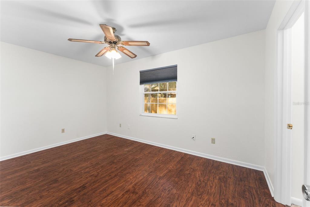 2026 Southwest 73rd Street Gainesville, FL 32607 - Photo 8 of 20 an empty room with wooden floor ceiling fan and windows