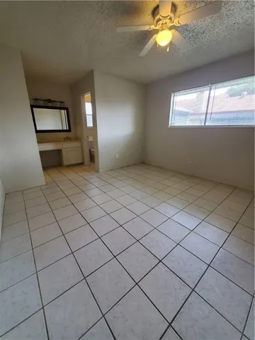 an empty room with windows and fan