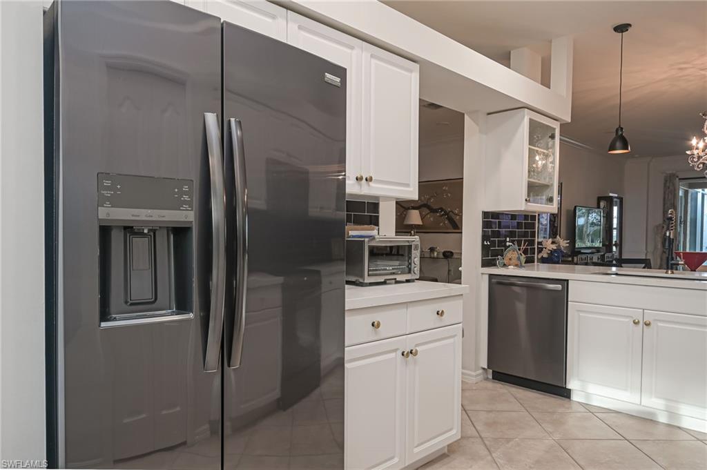 21533 Portrush Run Estero, FL 33928 - Photo 13 of 37 a kitchen with white cabinets and stainless steel appliances