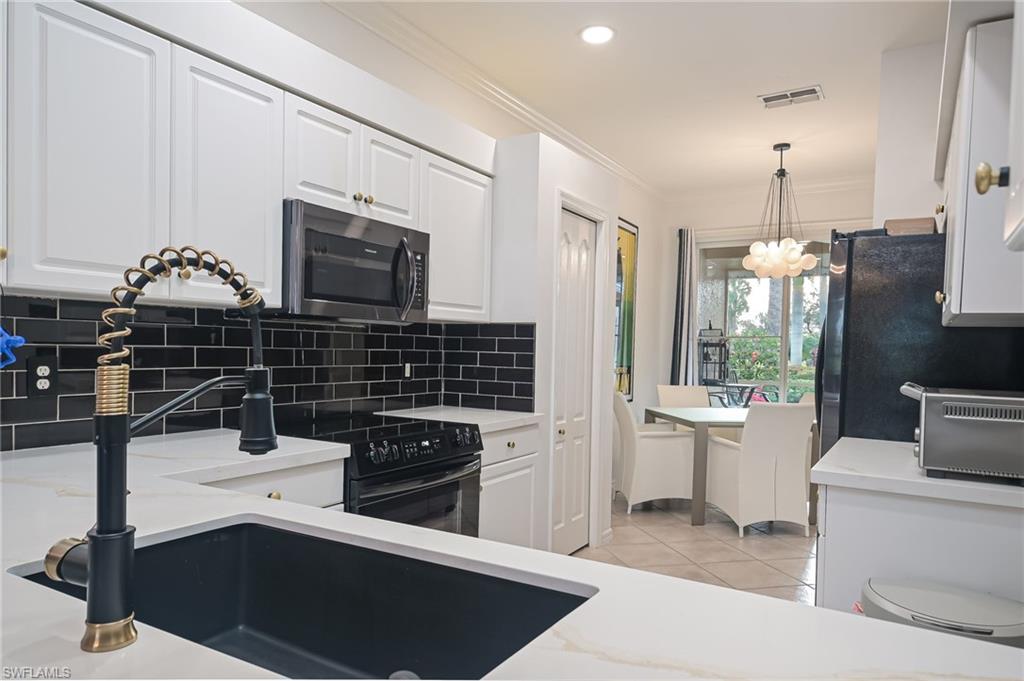 21533 Portrush Run Estero, FL 33928 - Photo 9 of 37 a kitchen with stainless steel appliances a sink stove and cabinets
