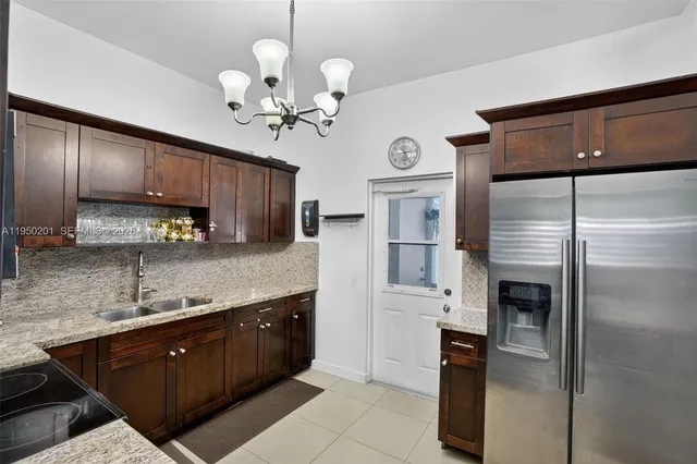a kitchen with stainless steel appliances granite countertop a refrigerator a sink dishwasher a stove and white cabinets