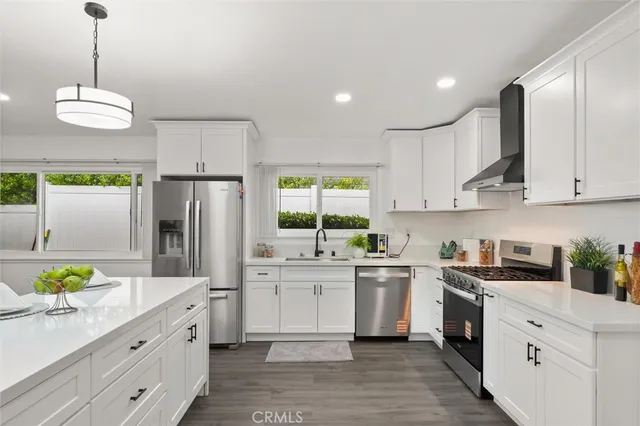 a kitchen with stainless steel appliances a white stove top oven a refrigerator a sink and dishwasher with white cabinets