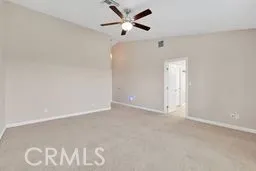 an empty room with a ceiling fan and carpet