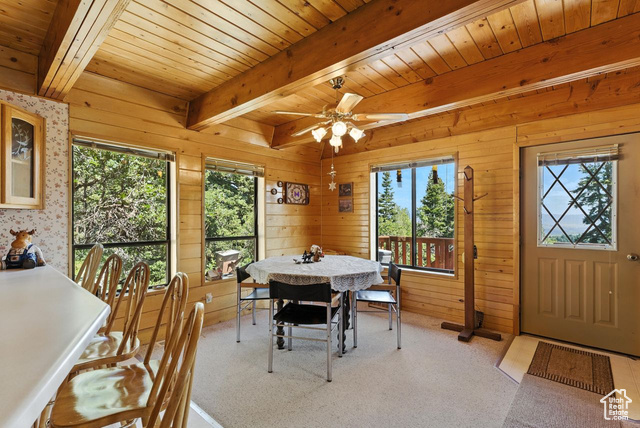 1180 Oak Road Coalville, UT 84017 - Photo 5 of 25 Dining space featuring a wood ceiling with exposed beams, a ceiling fan, wood walls, and light colored carpet
