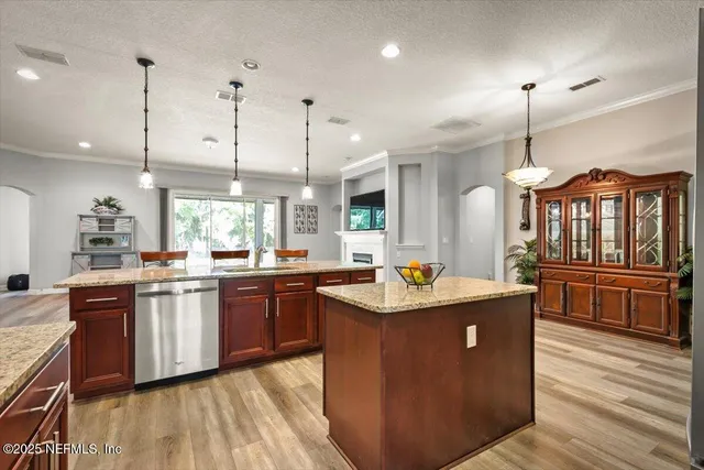 a kitchen with stainless steel appliances granite countertop a sink a stove and a wooden floors