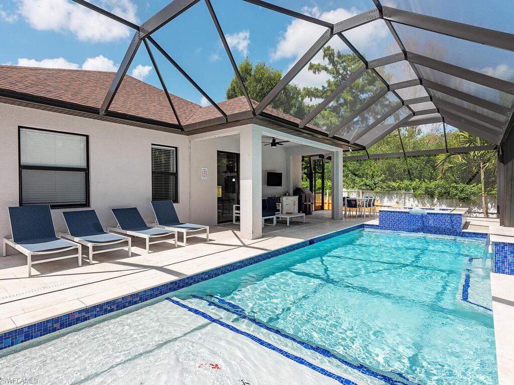 1021 Creech Road Naples, FL 34103 - Photo 1 of 12 View of swimming pool featuring a sunroom, a patio area, glass enclosure, ceiling fan, and a pool with connected hot tub