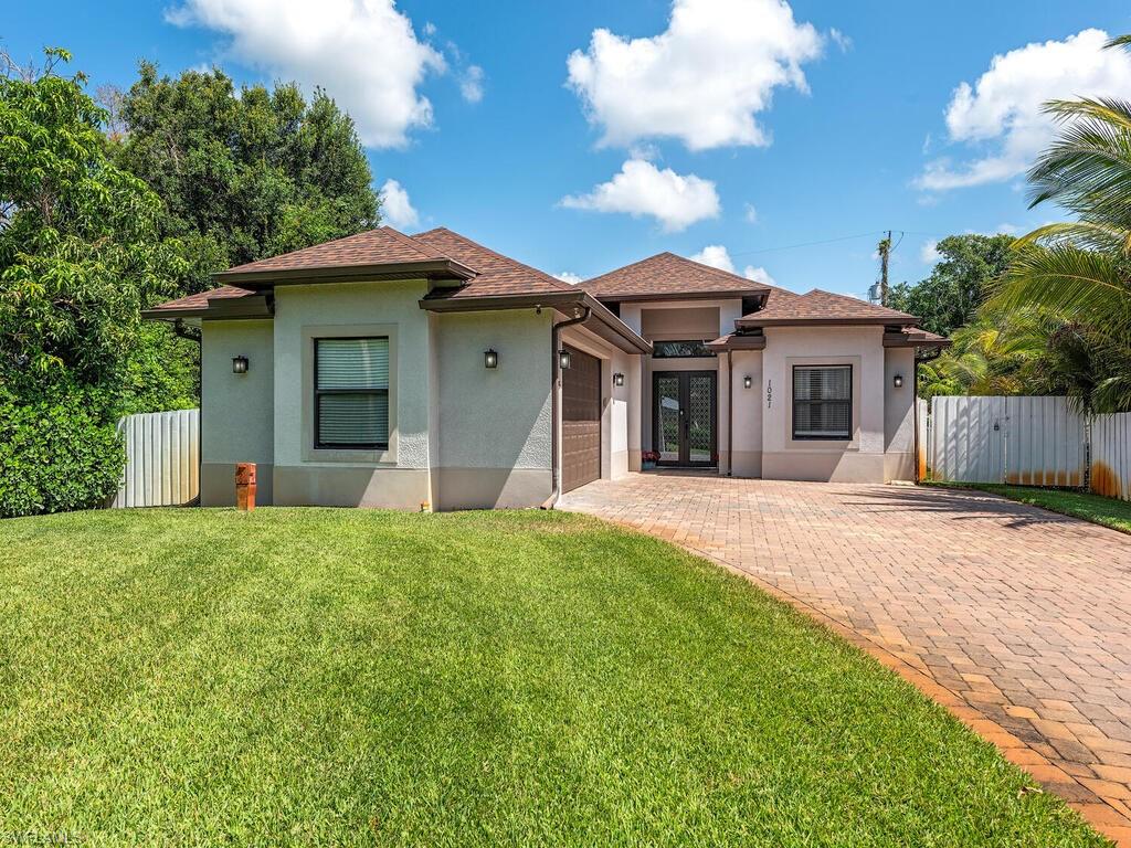 1021 Creech Road Naples, FL 34103 - Photo 12 of 12 View of front of property featuring an attached garage, stucco siding, decorative driveway, and roof with shingles