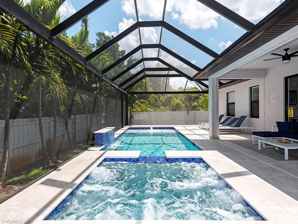 1021 Creech Road Naples, FL 34103 - Photo 2 of 12 View of swimming pool with glass enclosure, a patio, a pool with connected hot tub, ceiling fan, and a sunroom