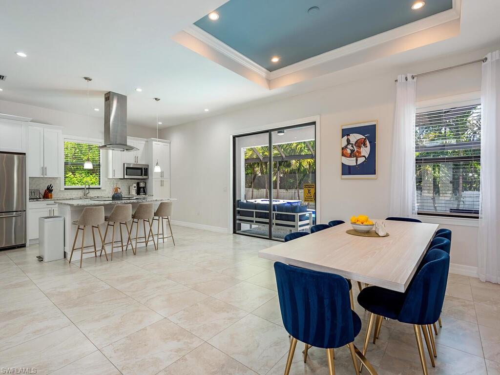 1021 Creech Road Naples, FL 34103 - Photo 5 of 12 Dining room with a tray ceiling, healthy amount of natural light, recessed lighting, crown molding, and light tile patterned floors