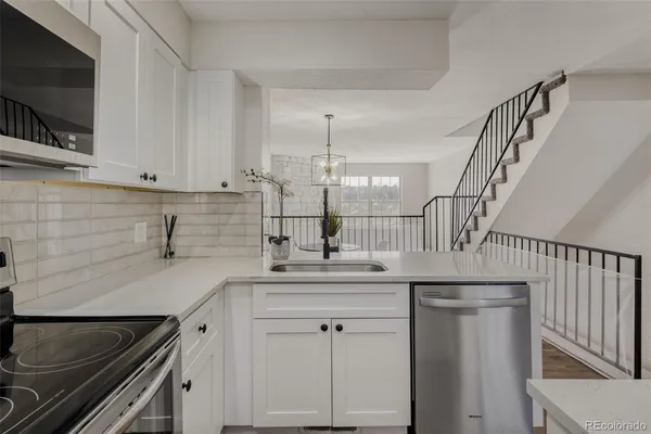 a kitchen with white cabinets sink and stainless steel appliances