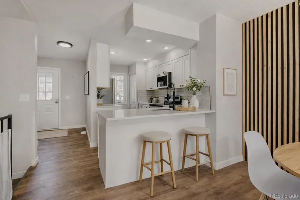 a kitchen with kitchen island stainless steel appliances a dining table chairs sink and cabinets